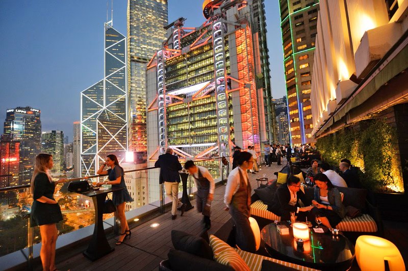 Evening crowd at Club Ill Repute rooftop bar in Hong Kong, overlooking the city’s illuminated skyline