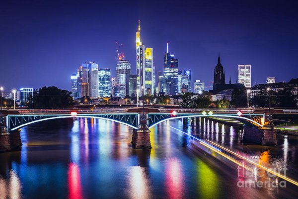 Frankfurt skyline at night with colorful reflections on the Main River and illuminated bridge